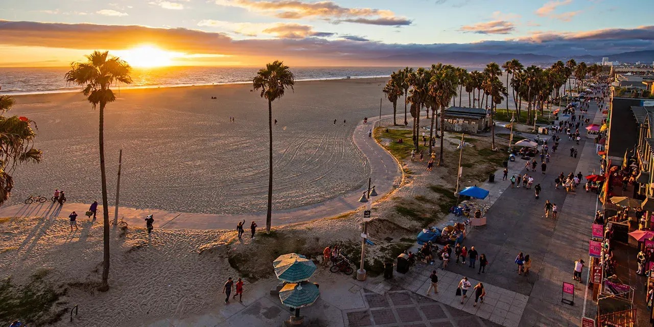 An aerial view of a beach with palm trees at sunset.