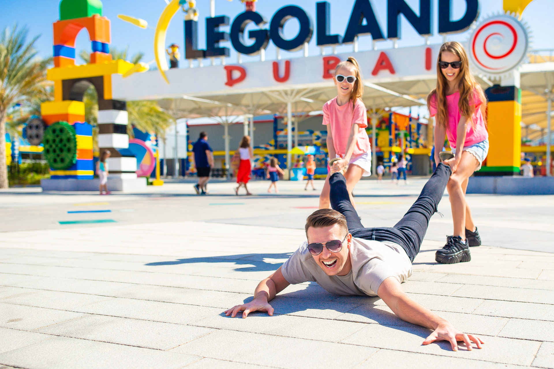 A man is laying on the ground in front of a legoland sign.