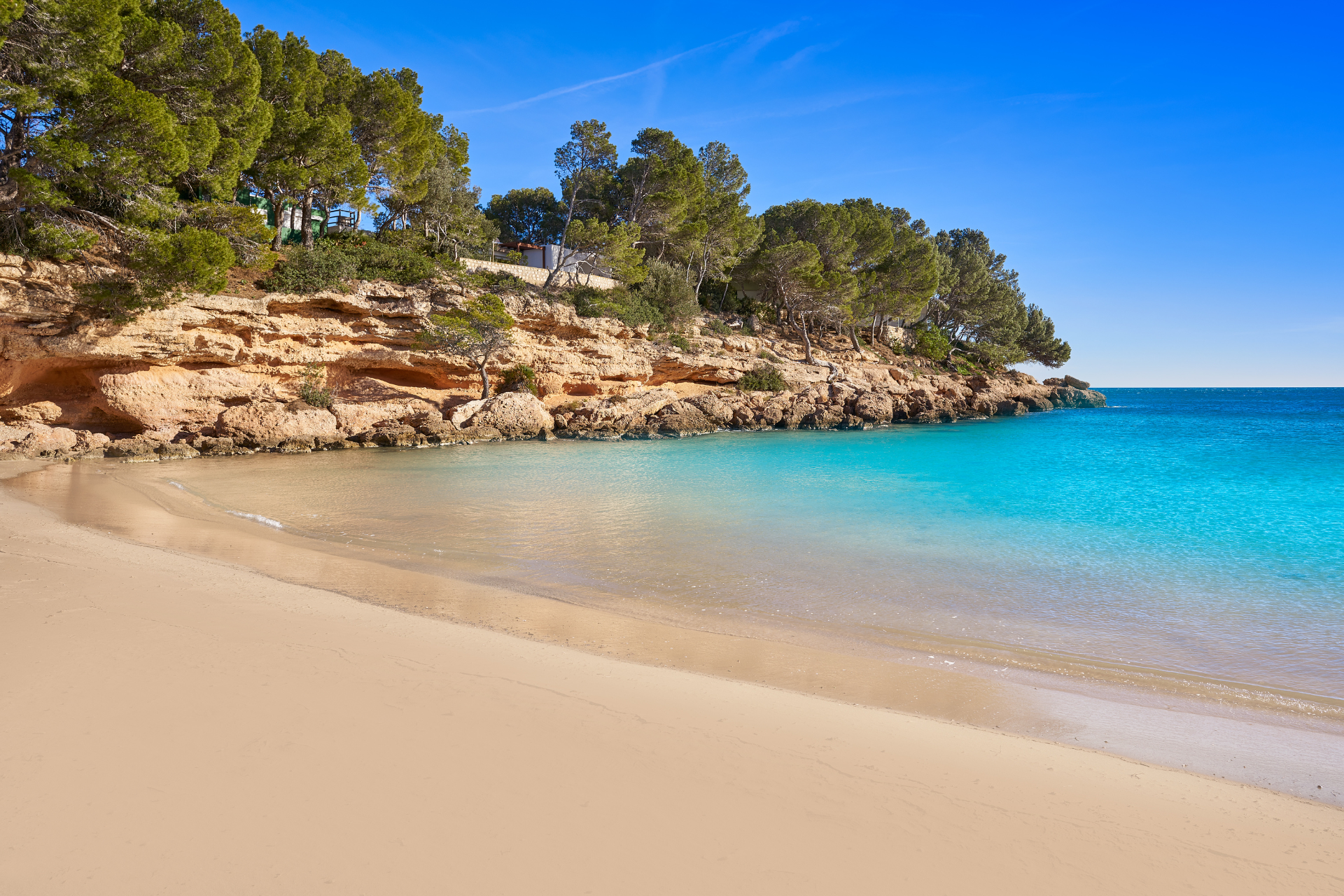 A sandy beach surrounded by rocks and trees next to a body of water.