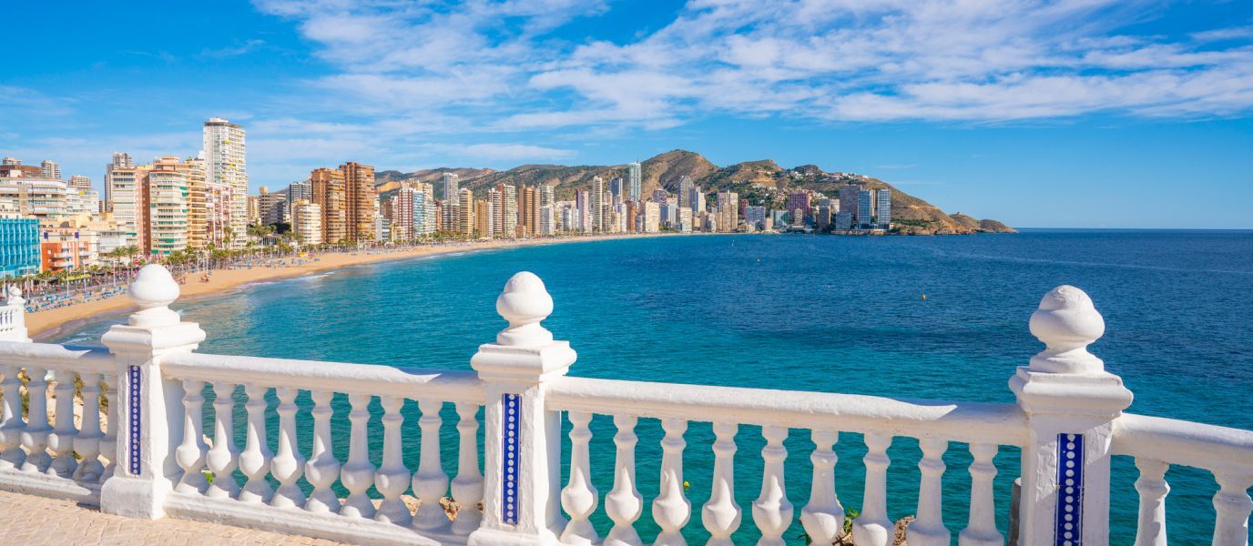 A view of a city from a balcony overlooking the ocean.