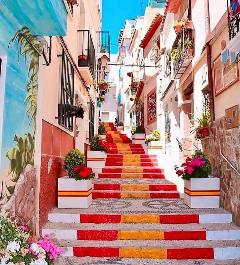 A narrow alleyway with stairs painted red yellow and white