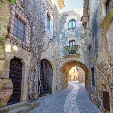 A narrow alleyway between two stone buildings with a stone archway.