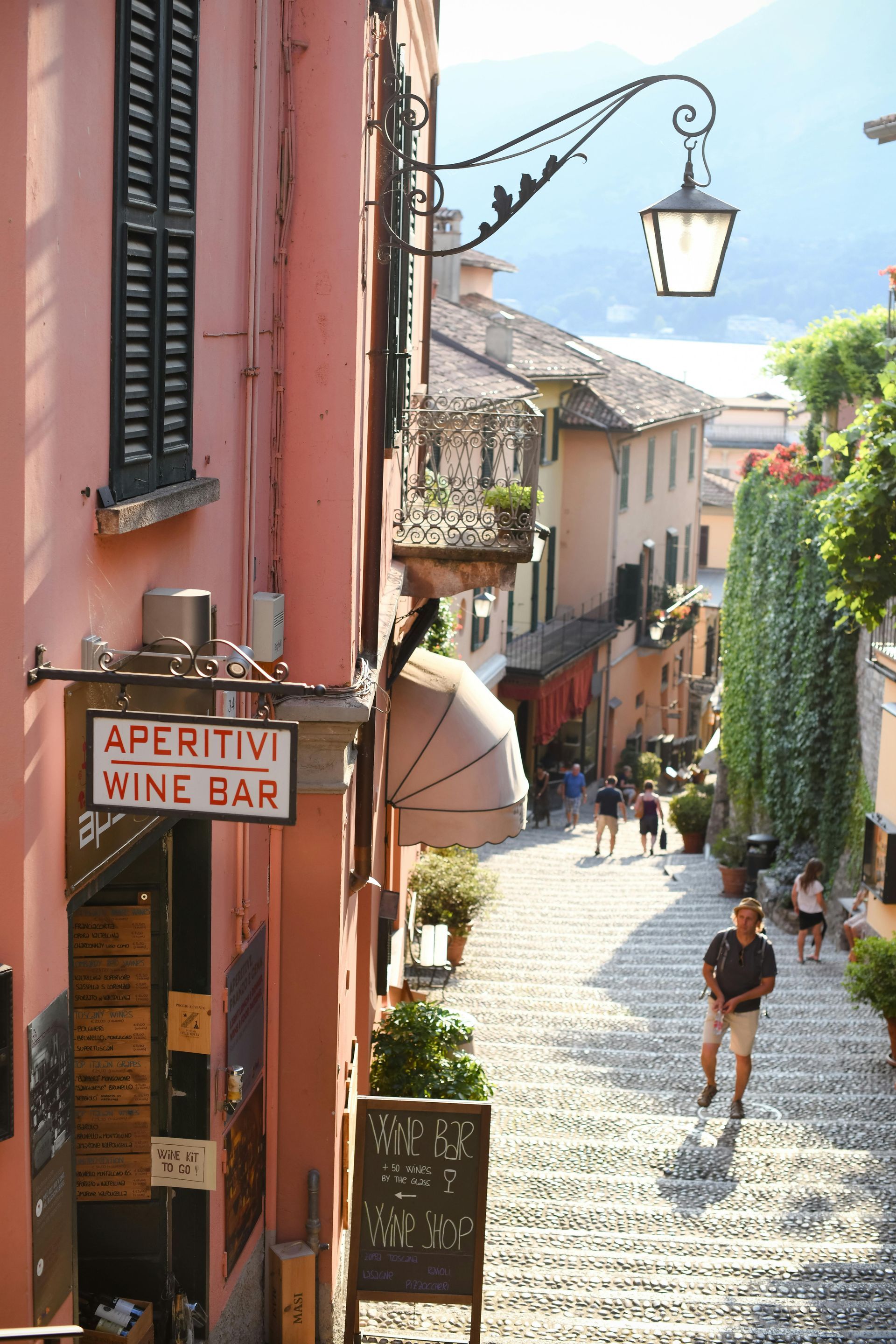 A man is walking down a narrow street next to a wine bar.