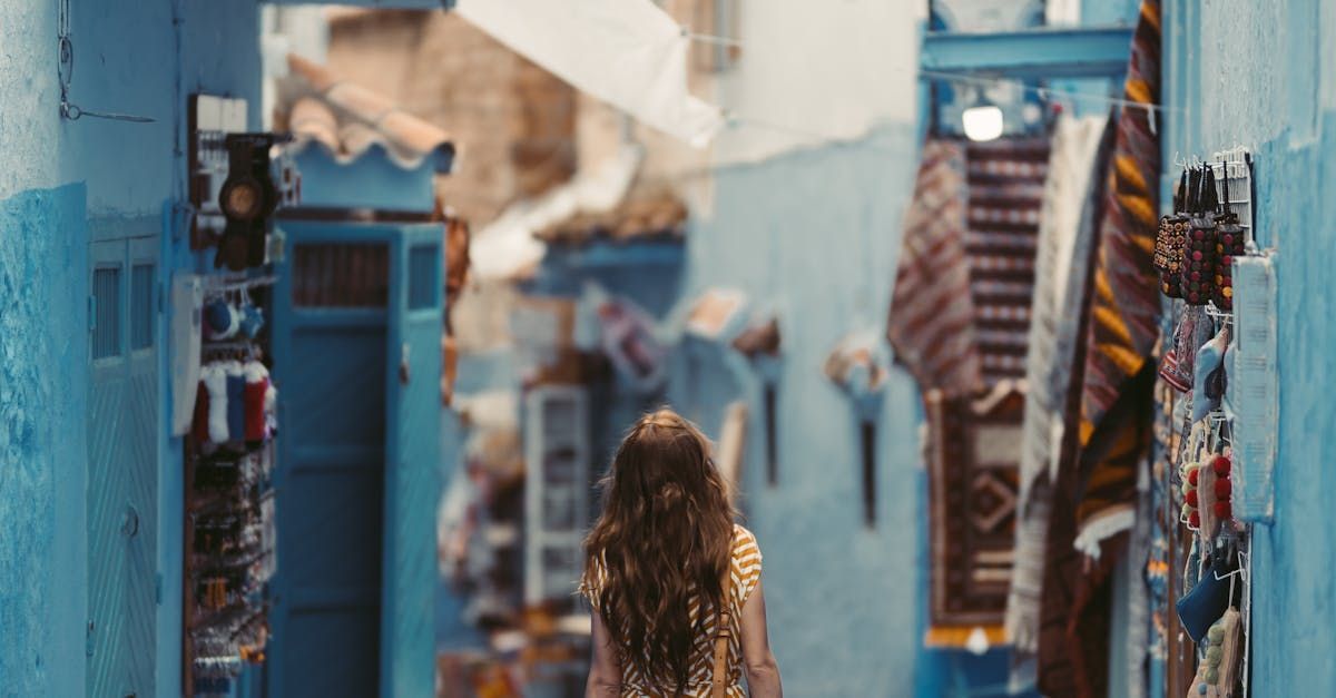 A woman is walking down a blue alleyway.