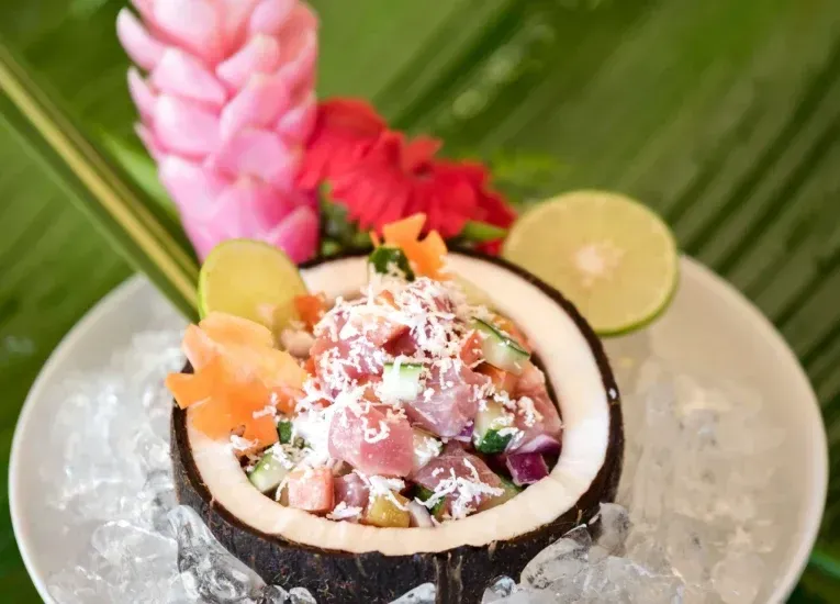 A close up of a coconut filled with food on ice on a plate.