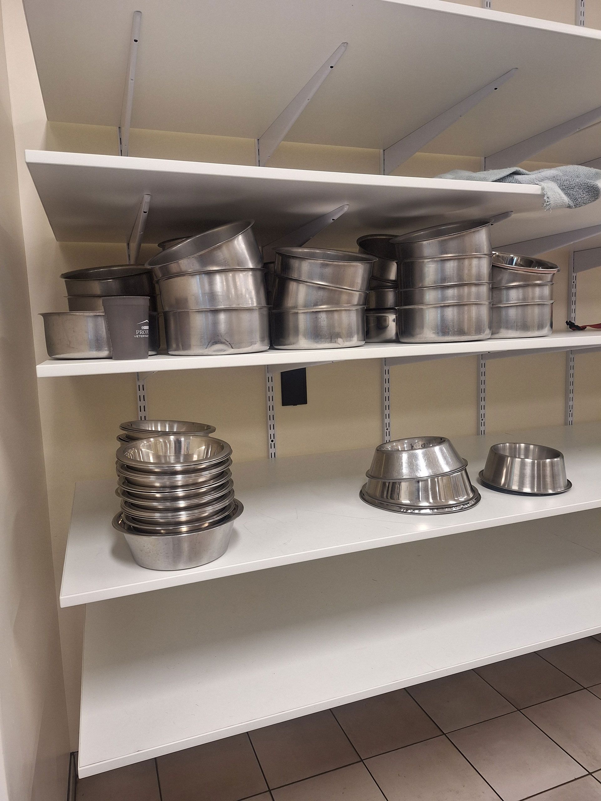 A shelf filled with stainless steel bowls and pans.