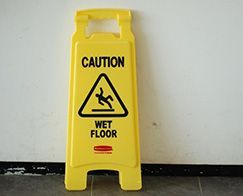 Yellow caution sign on a wet floor, warning of slip hazard.