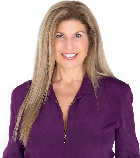 Smiling woman with long blonde hair wearing a purple zip-up top on a white background
