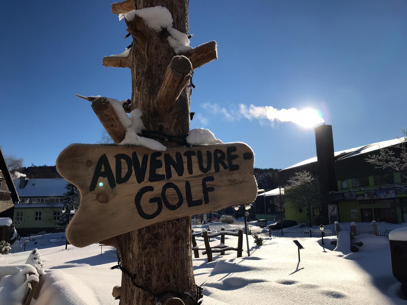 Ein Holzschild an einem Baum sagt Adventure Golf