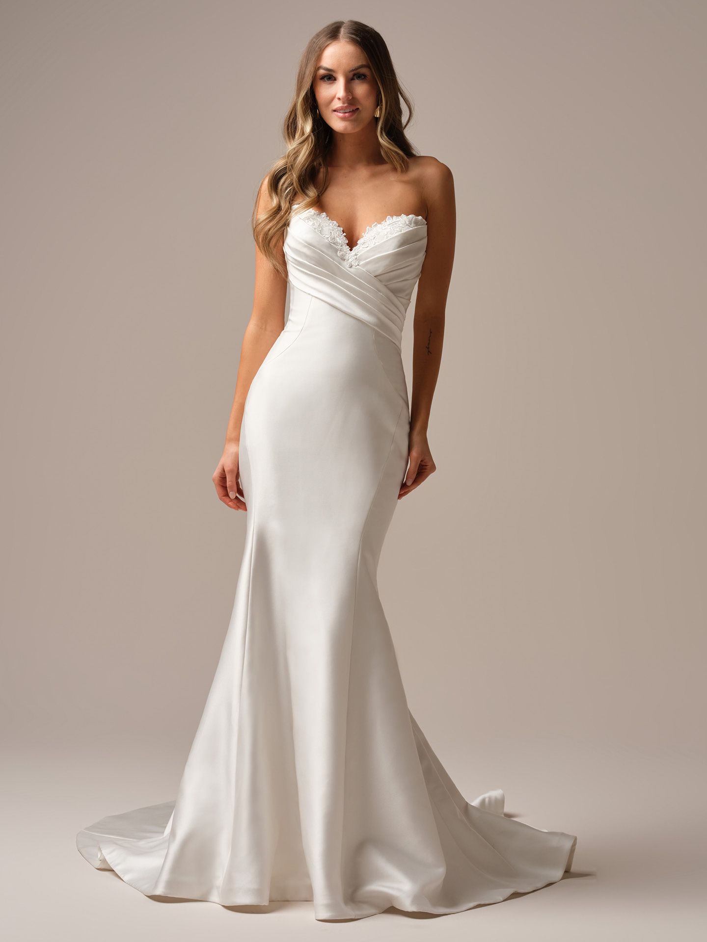 A woman in a white wedding dress is standing on a white background.