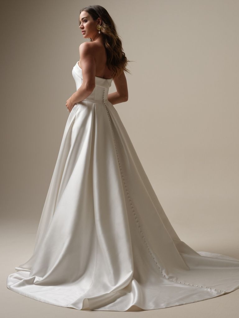 A woman in a white wedding dress is standing on a white background.