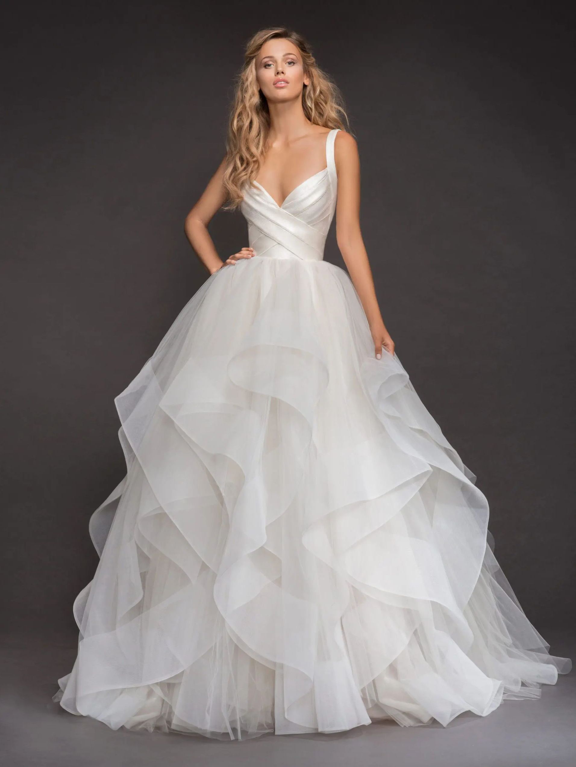 A woman is wearing a white wedding dress with ruffles on the skirt.