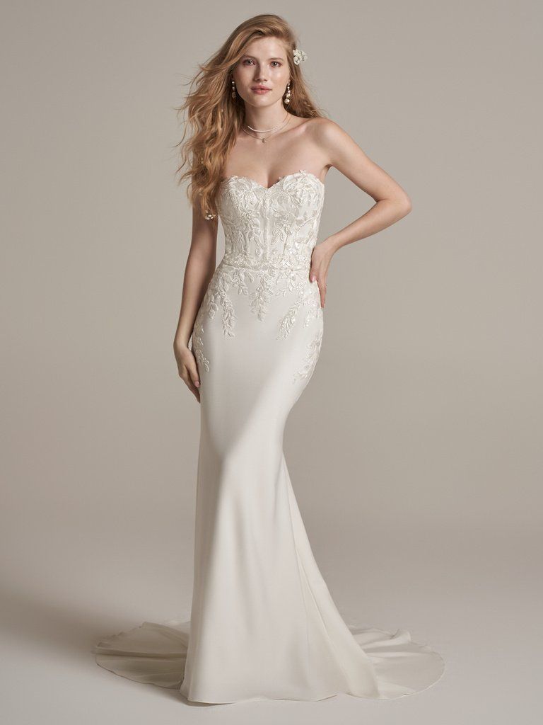 A woman in a wedding dress is standing on a beach.