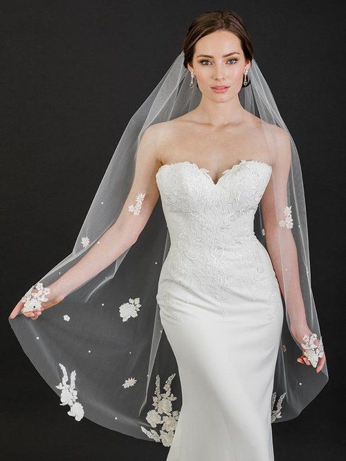 A woman in a white wedding dress and veil is standing on a balcony.