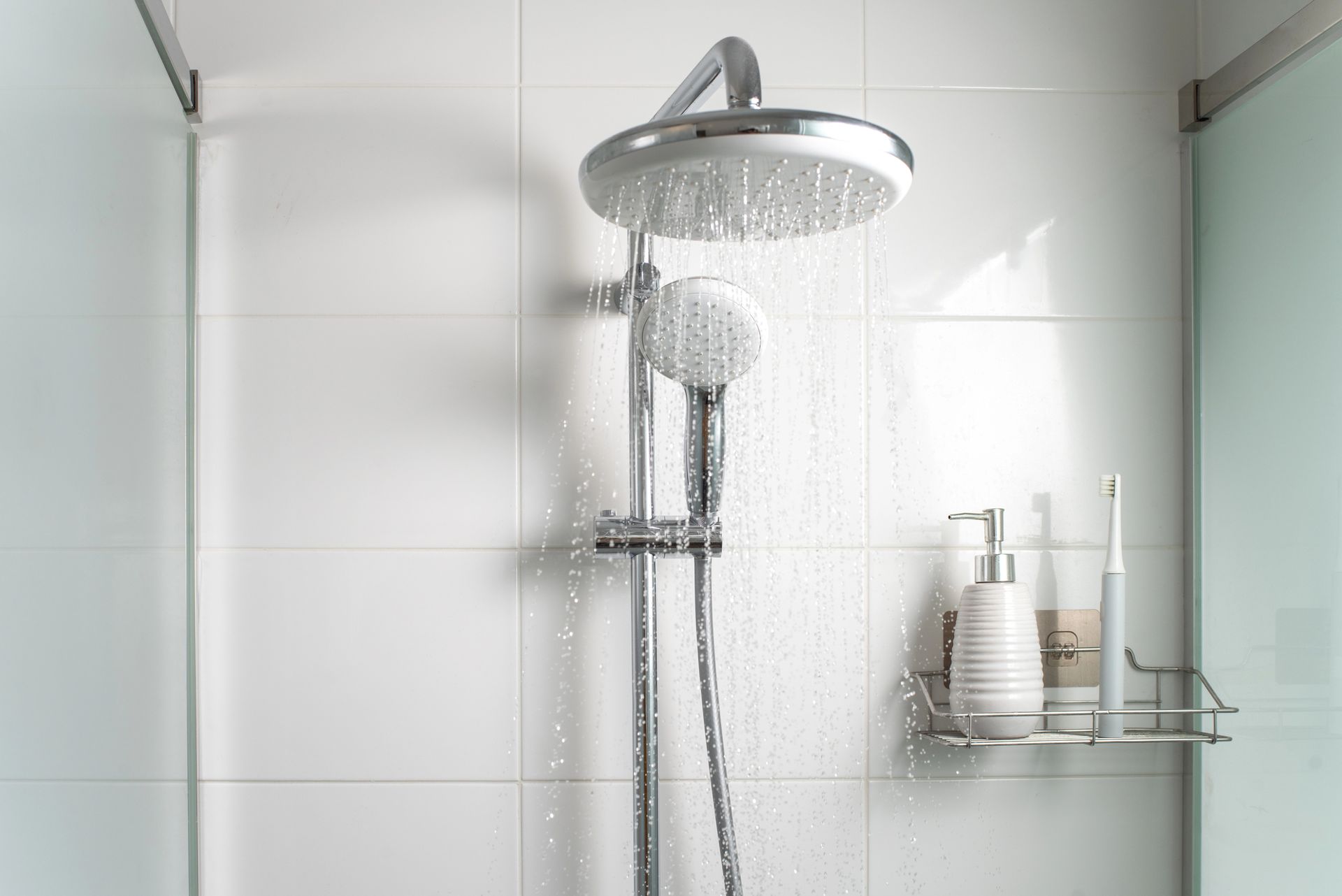 Modern shower with glass walls, chrome fixtures, and white tiled walls