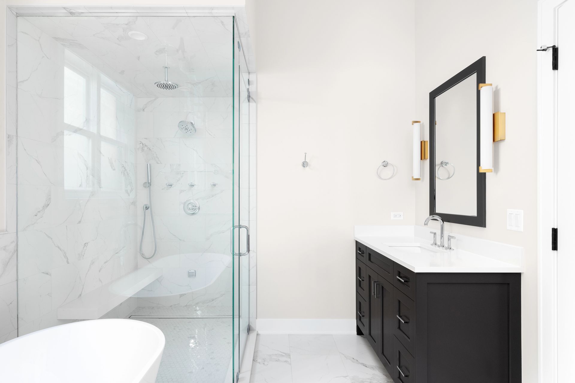 Bright modern bathroom with glass shower and black vanity with mirror.