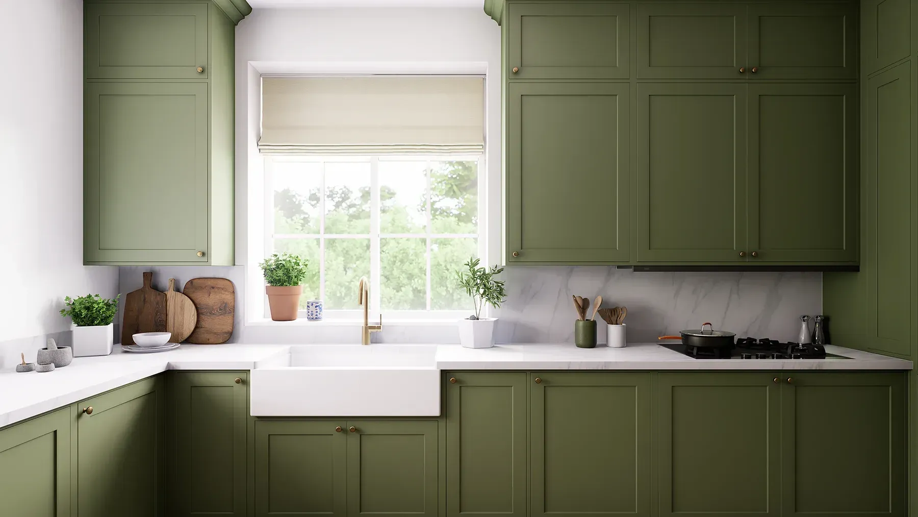 Green kitchen with white countertops and sink, window with neutral shade, and wood cutting boards.