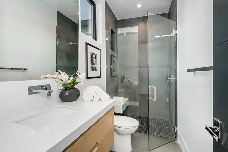 Modern bathroom with white vanity, mirror, toilet, and glass shower enclosure