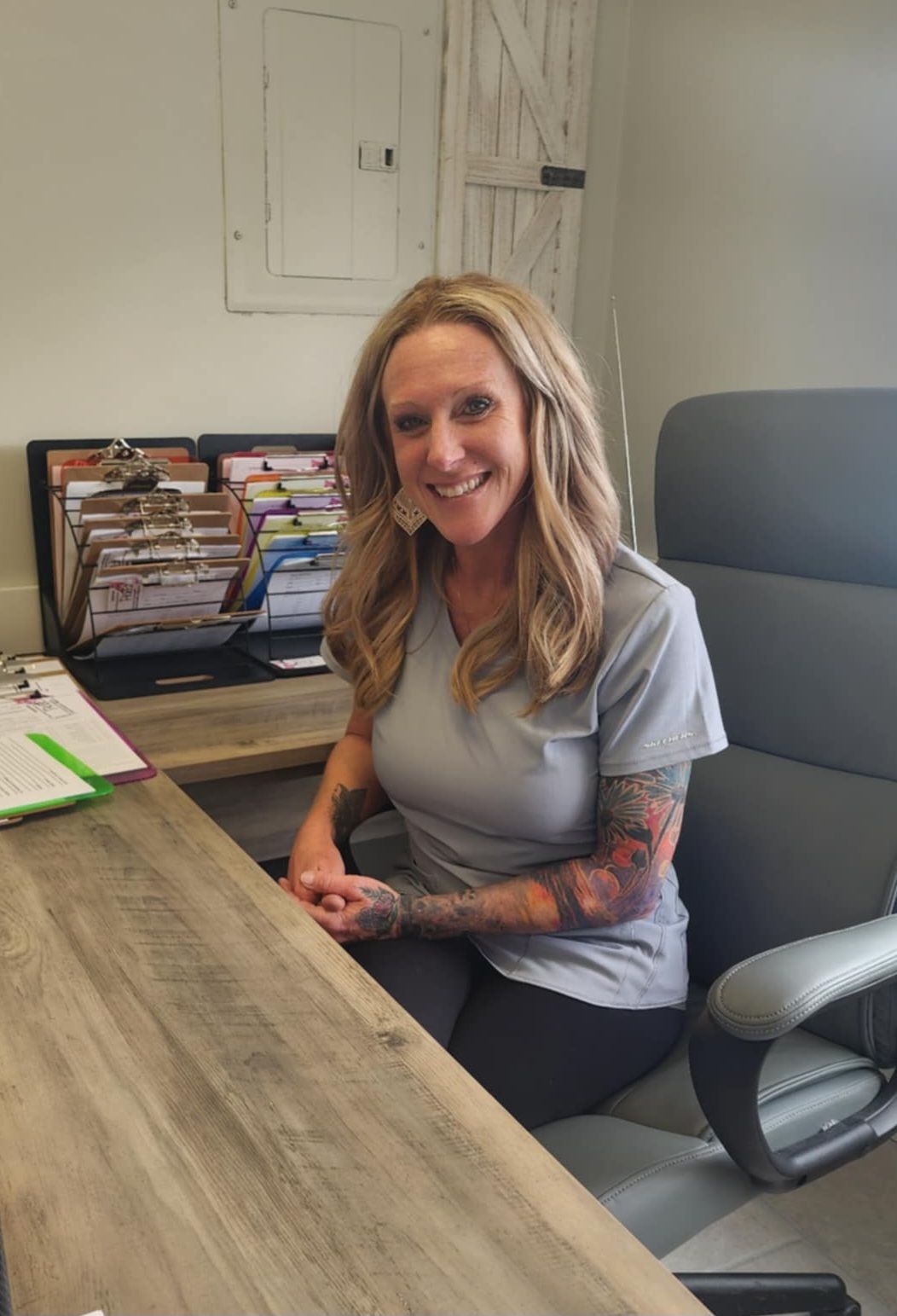 A woman is sitting at a desk in an office smiling.