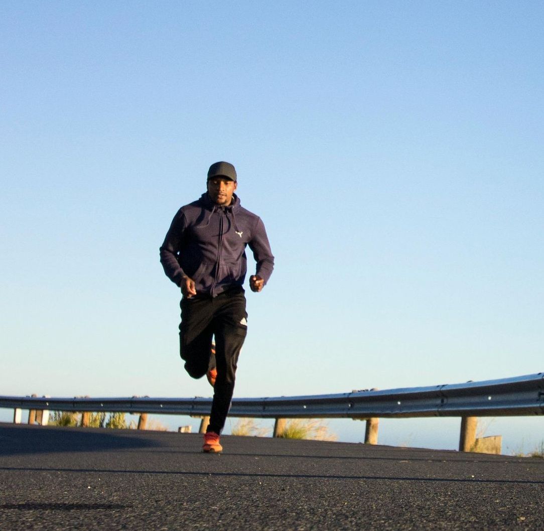 A man in a purple jacket is running down a road