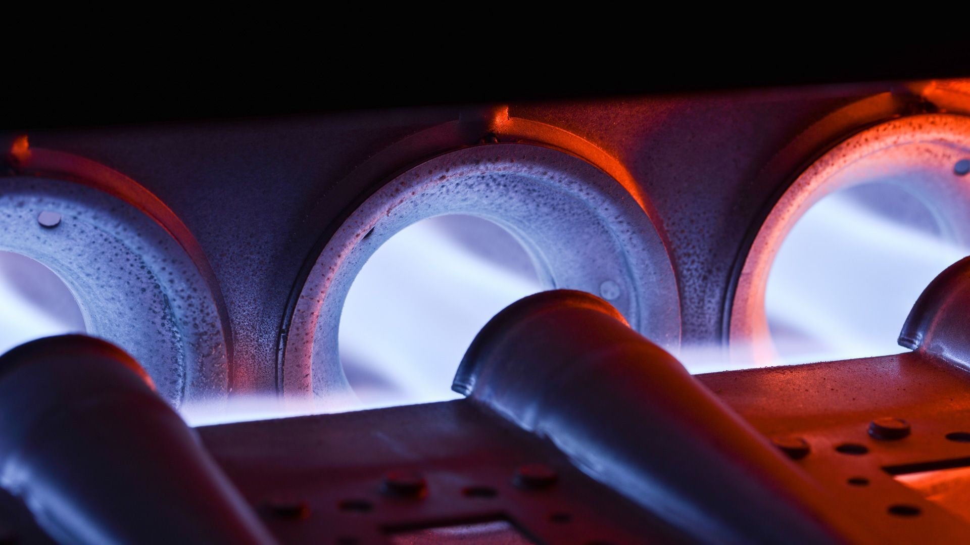 A close up of a gas burner with flames coming out of it.