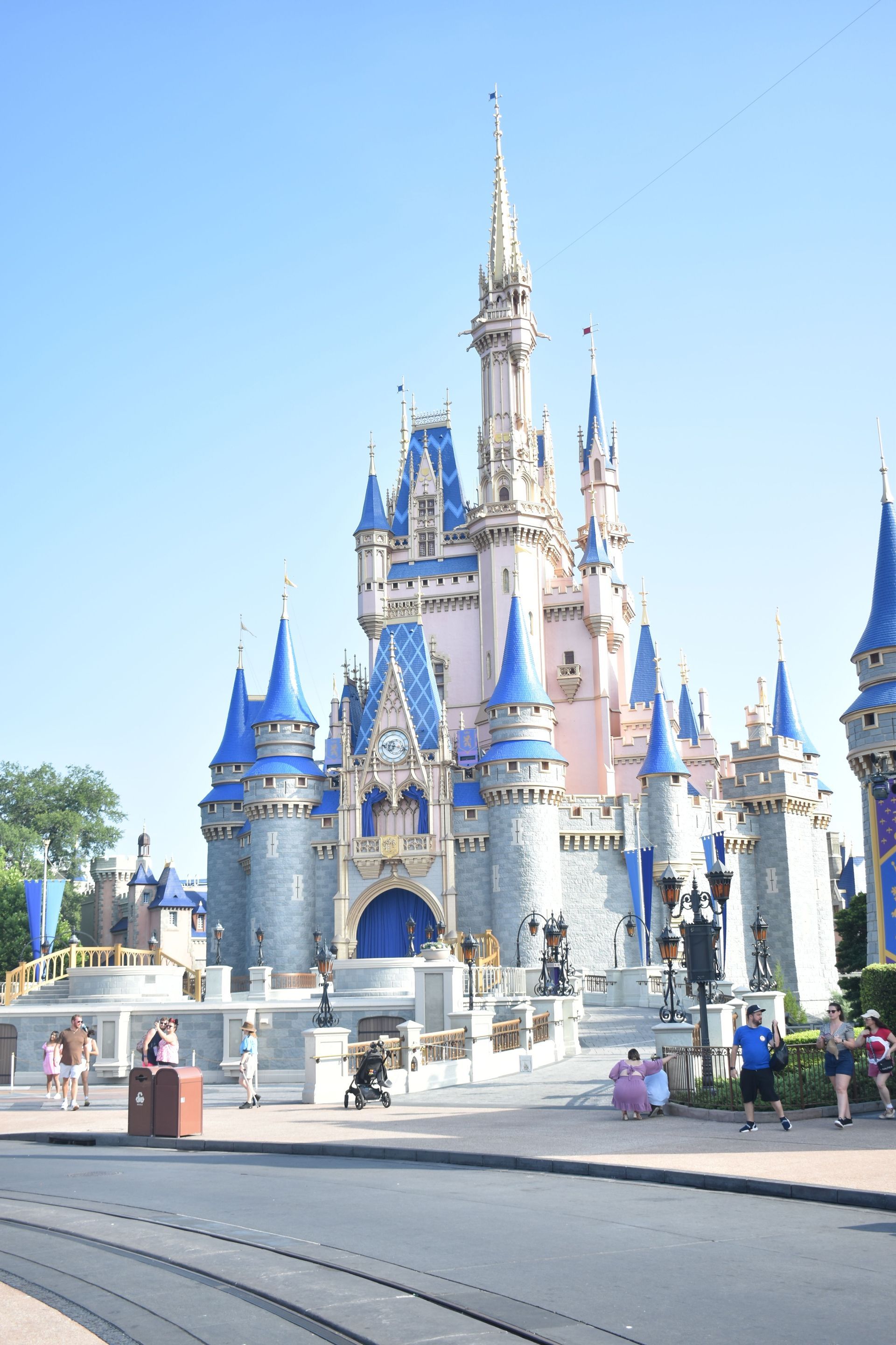 Cinderella Castle at Disney World under a clear blue sky, with visitors in front