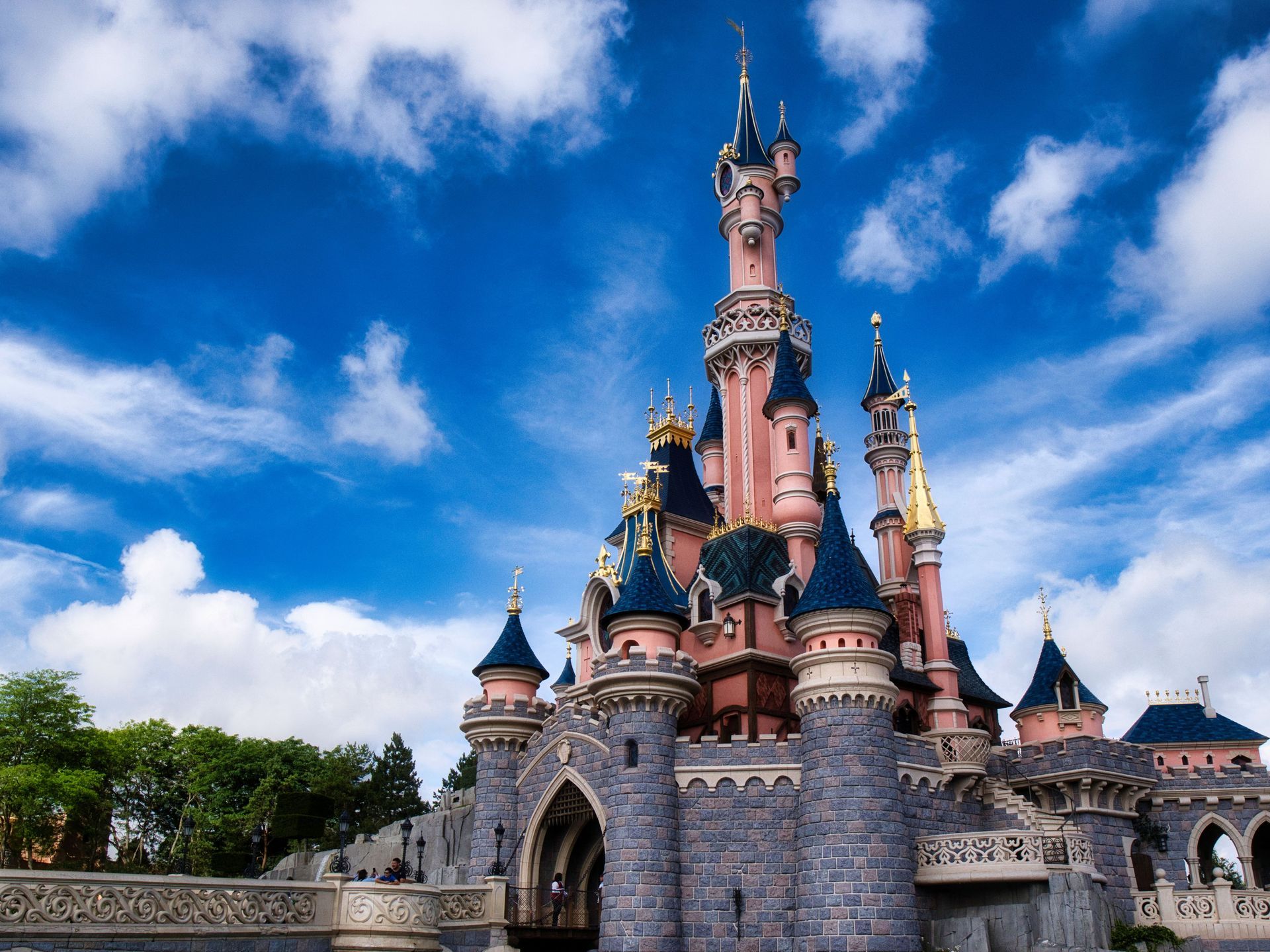 Pink castle with blue turrets under a bright blue sky with white clouds