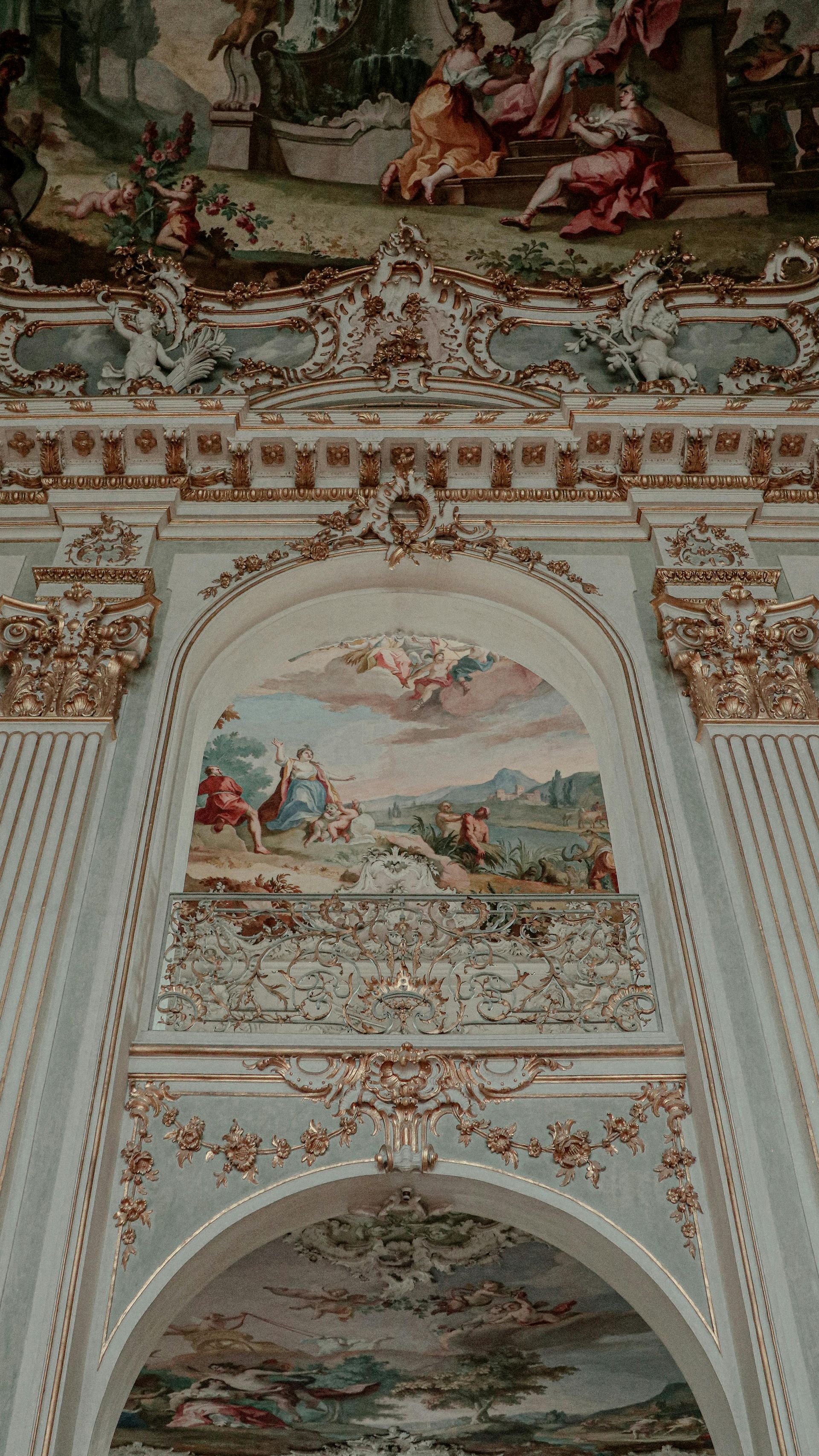 Ornate ceiling frescoes and gold-trimmed arches in a pastel-blue, lavishly decorated interior