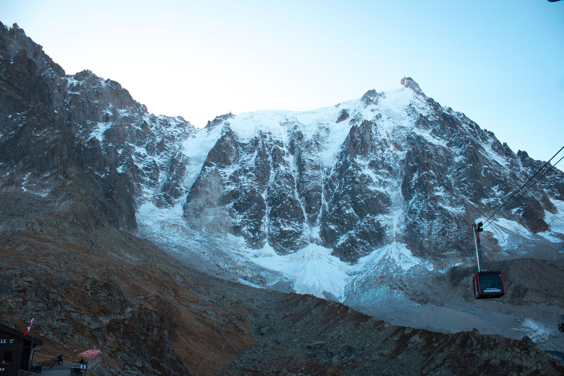 Snow-covered mountain peaks above a rocky valley with a cable car on the right