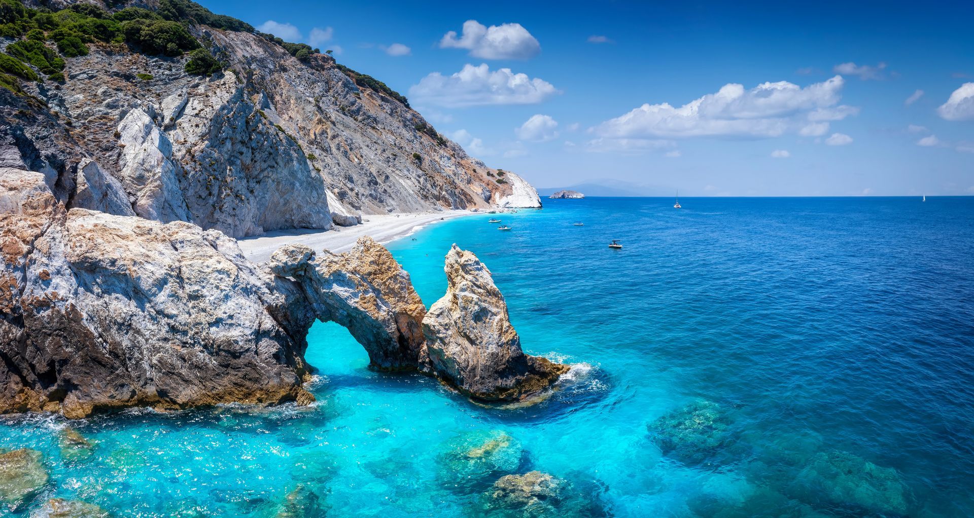 Rocky seaside cove with turquoise water, white cliffs, and a clear blue sky