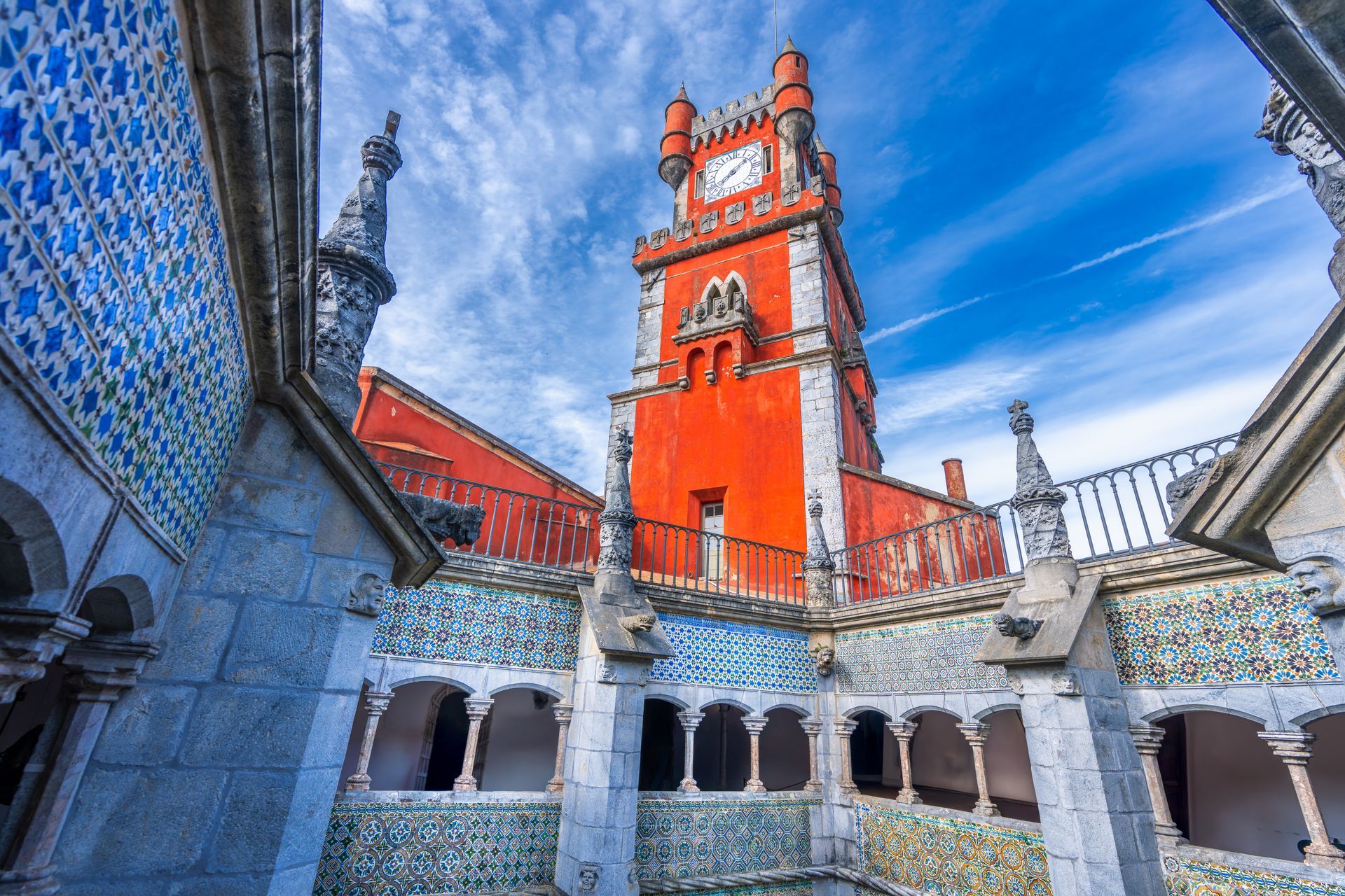 Courtyard view of a colorful cathedral with orange towers and blue patterned tile walls under a bright sky