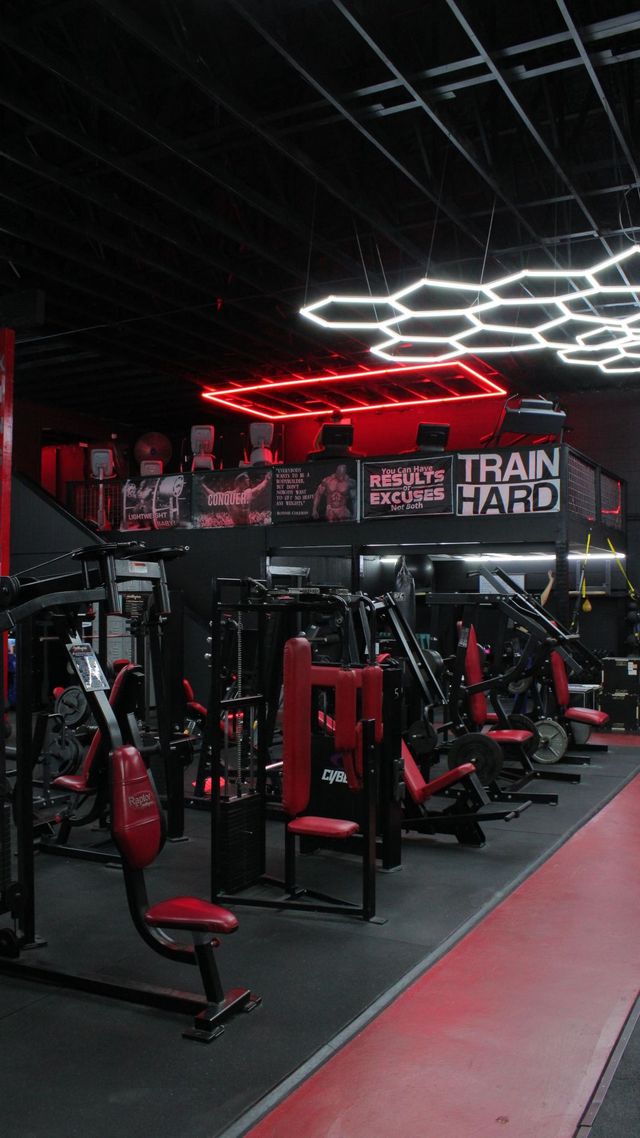 Gym interior with red-carpeted aisle, exercise machines, and hexagonal ceiling lights