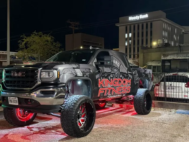 Black lifted GMC truck with red underglow and KINGDOM FITNESS logo parked at night