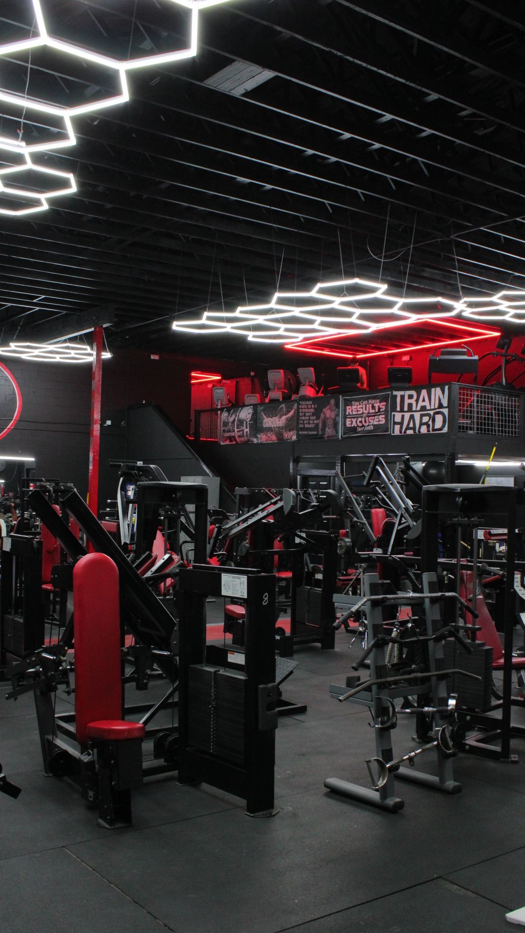 Modern gym interior with black and red equipment under hexagonal ceiling lights