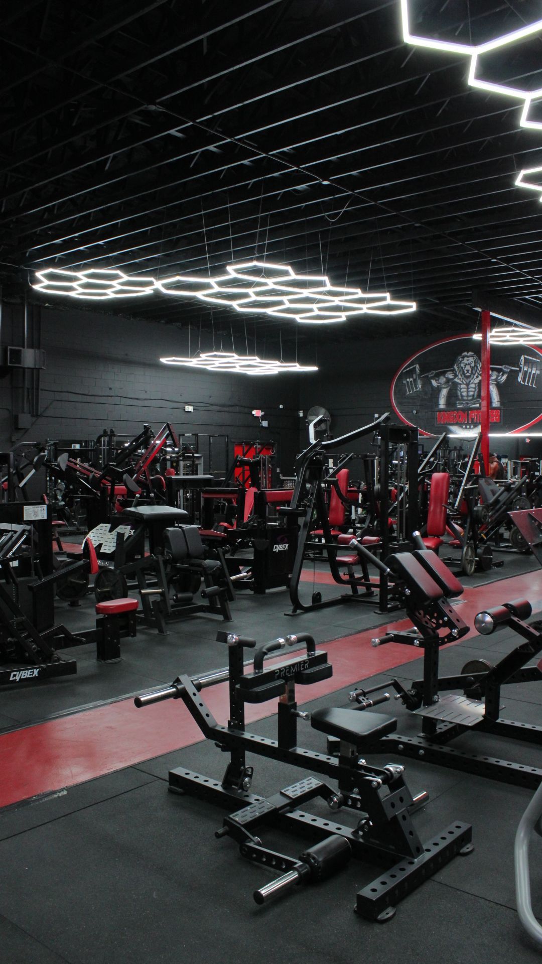 Modern gym interior with red and black equipment and geometric ceiling lights