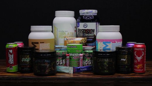 Wooden shelf stocked with assorted protein and supplement canisters, bottles, and small packaged items.