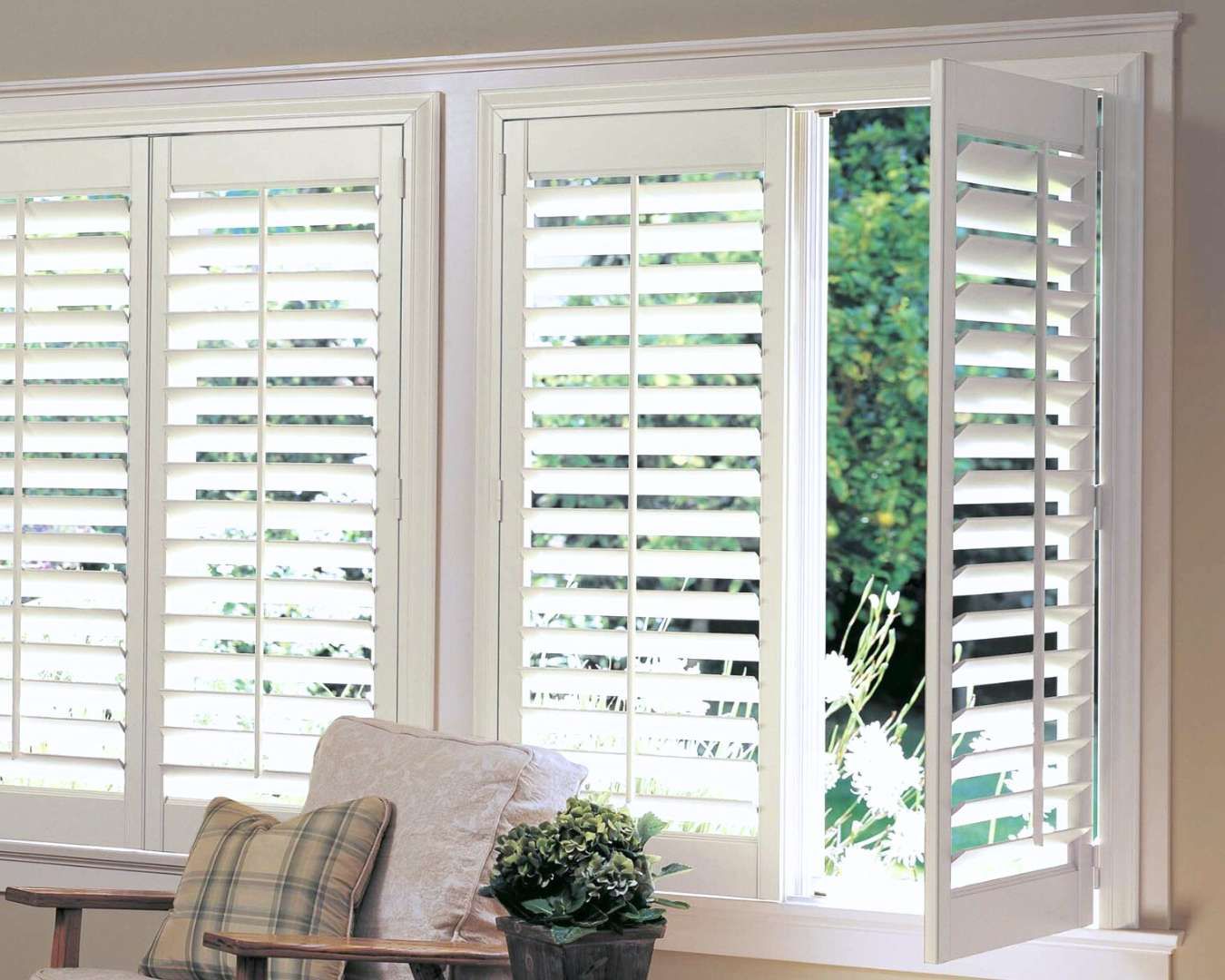 A living room with white shutters on the windows