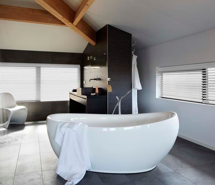 Luxurious bathroom with Venetian blinds, a freestanding bathtub, and modern fixtures.