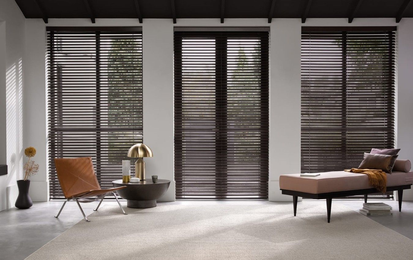 A living room with a couch , chair , table and shutters on the windows.