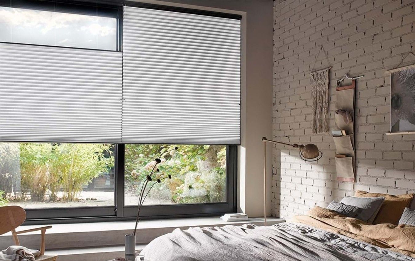 A bedroom with a bed and a window with blinds on it.