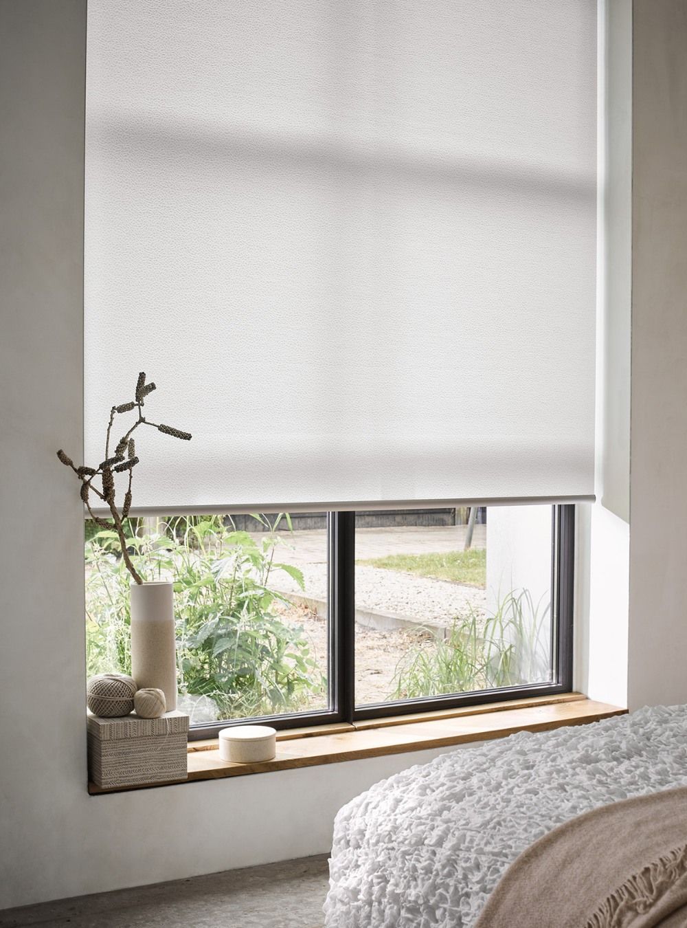 A bedroom with a bed and a window with a white blind on it.