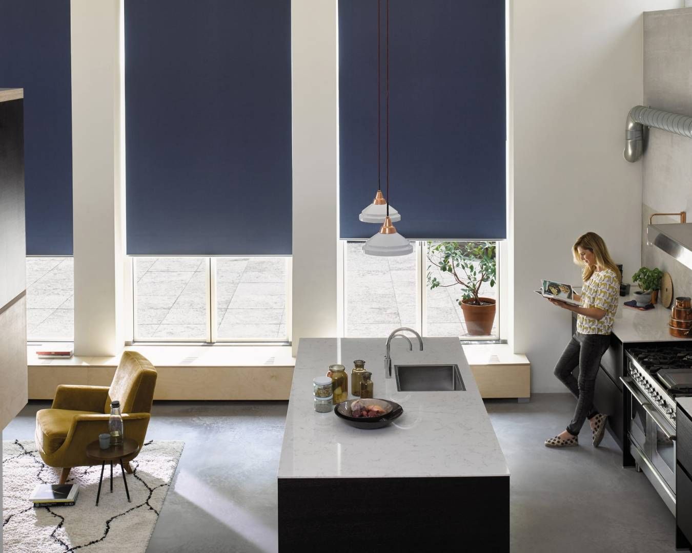 A kitchen dining area with block-out roller blinds, featuring a modern table setup and large windows.