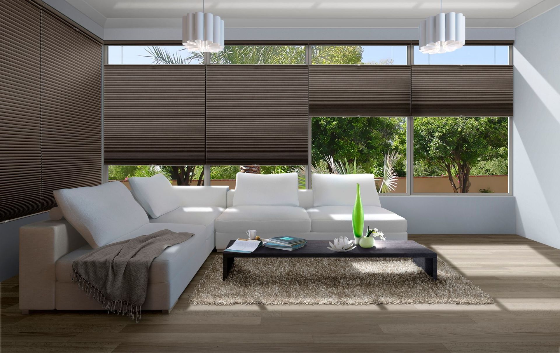 A living room with a couch, coffee table, and large windows with honeycomb blinds.