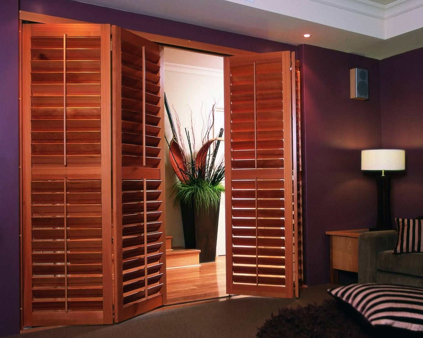 A living room with purple walls and wooden shutters