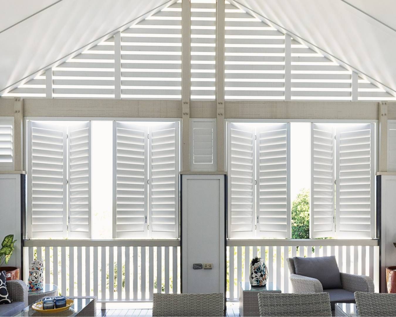 A living room with a vaulted ceiling and white shutters