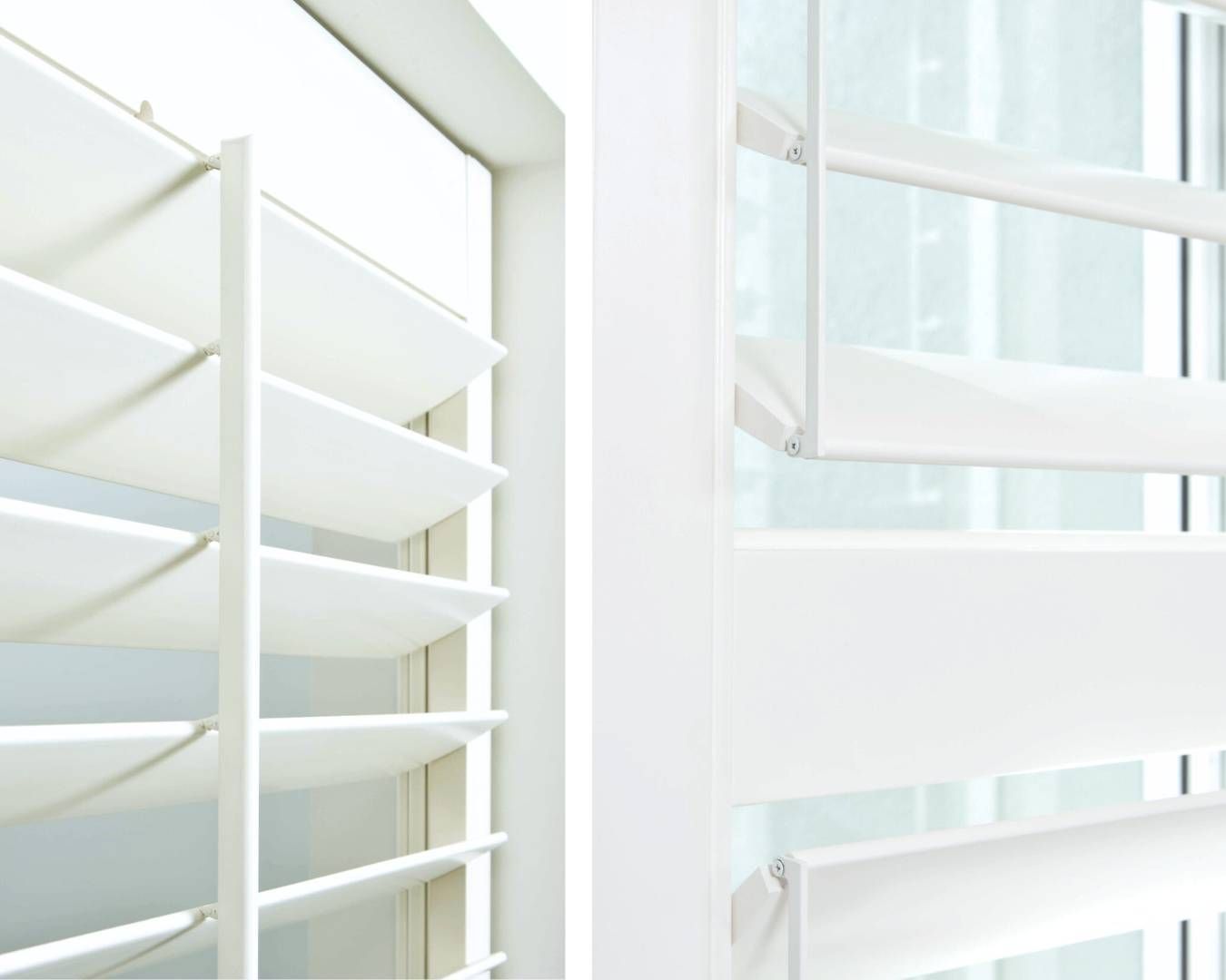 A close up of a window with white shutters on it