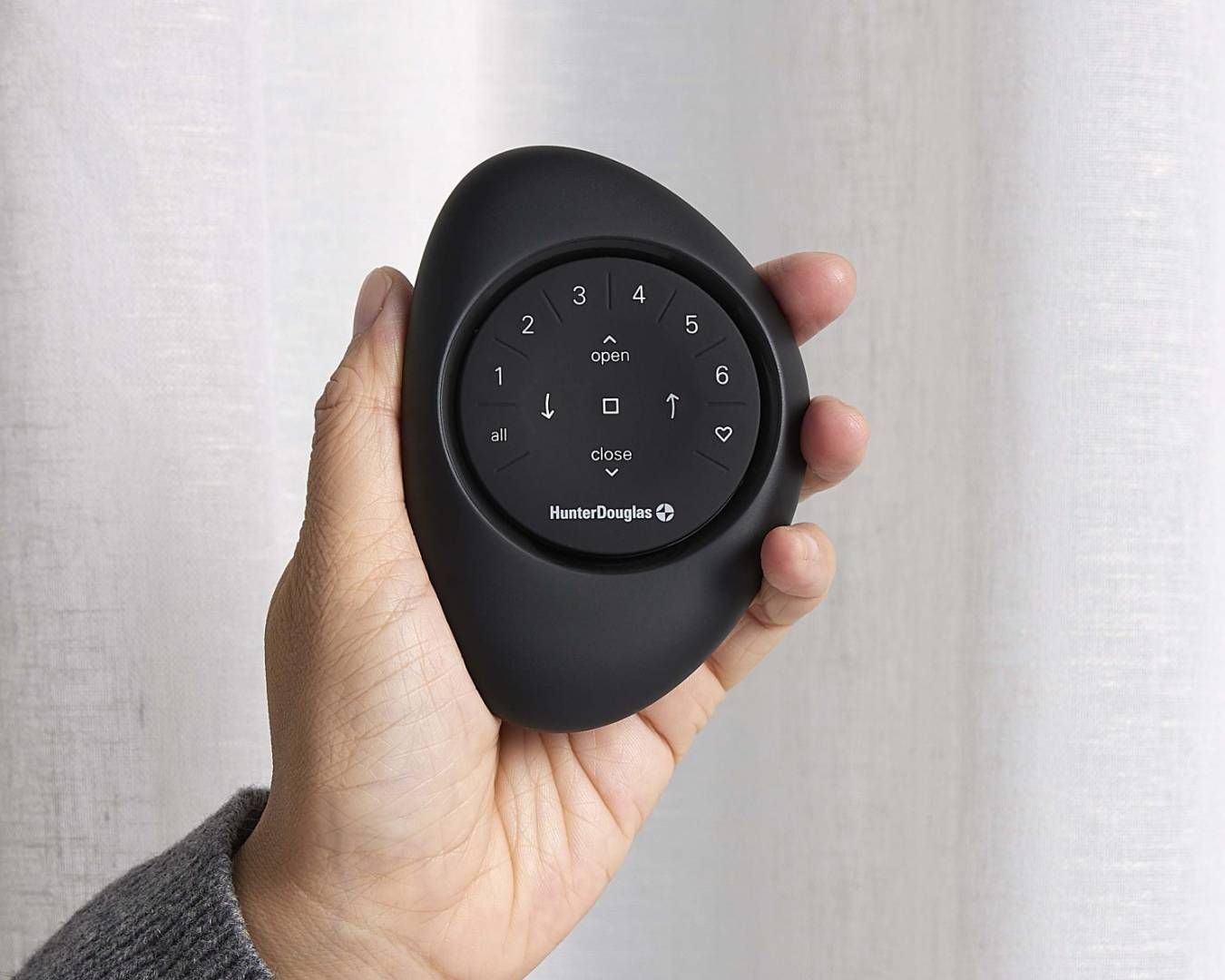 A person is holding a black remote control in their hand