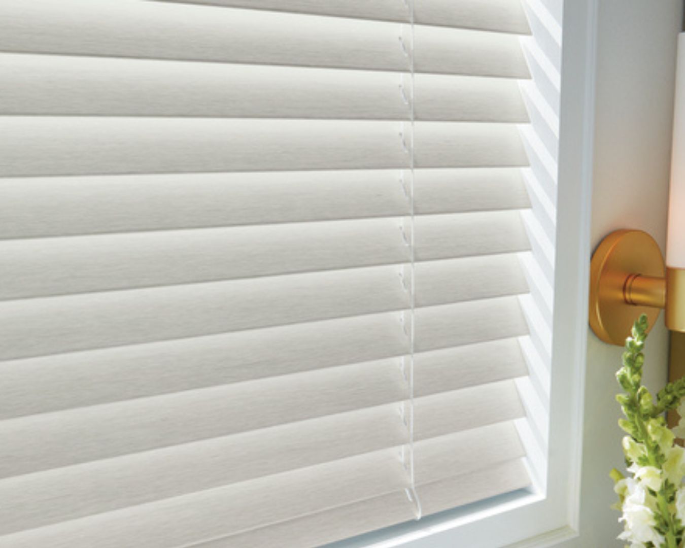 A white blind is hanging on a window next to a lamp.