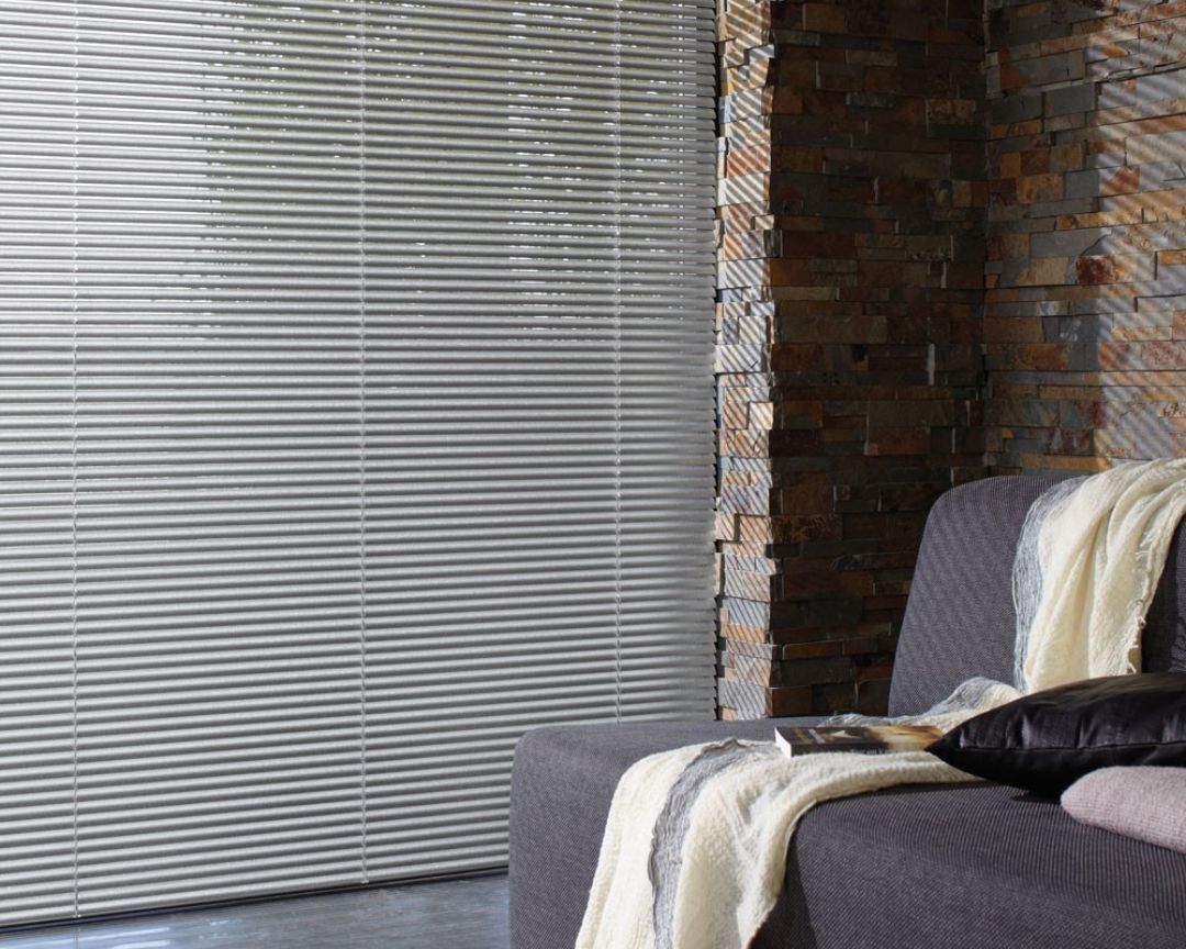 A living room with a couch and a window with blinds.