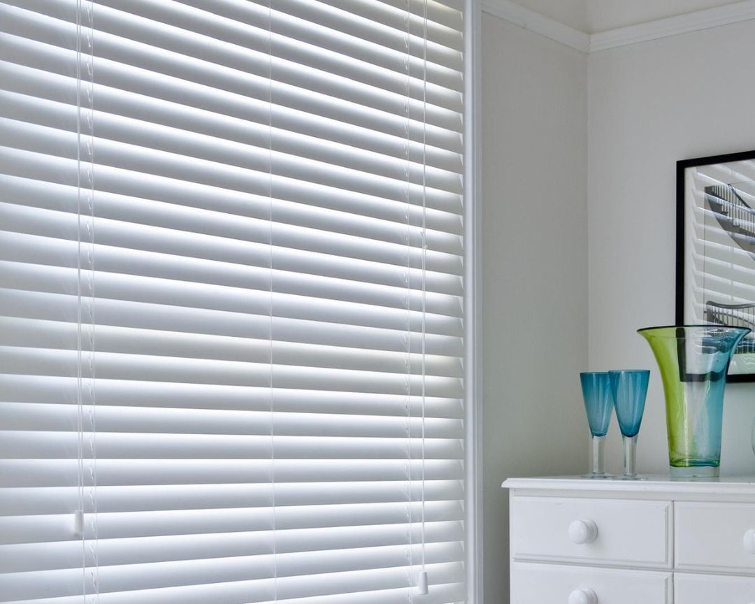A room with white blinds and a white dresser